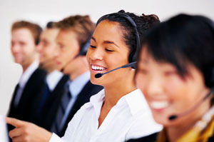 female call center agent smiling on the phone surrounded by other agents