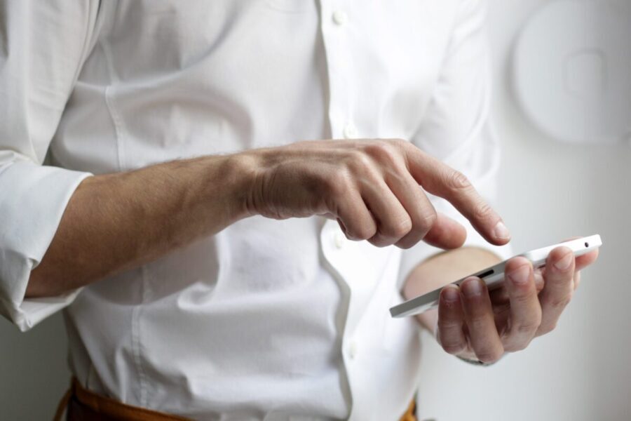 man in white button up shirt touching his phone's touch screen