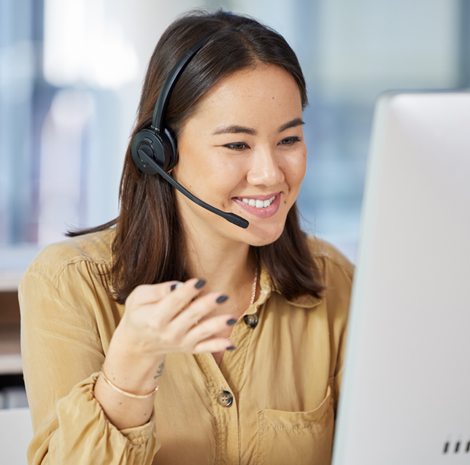 Dark-haired female wearing a headset and looking at a computer monitor