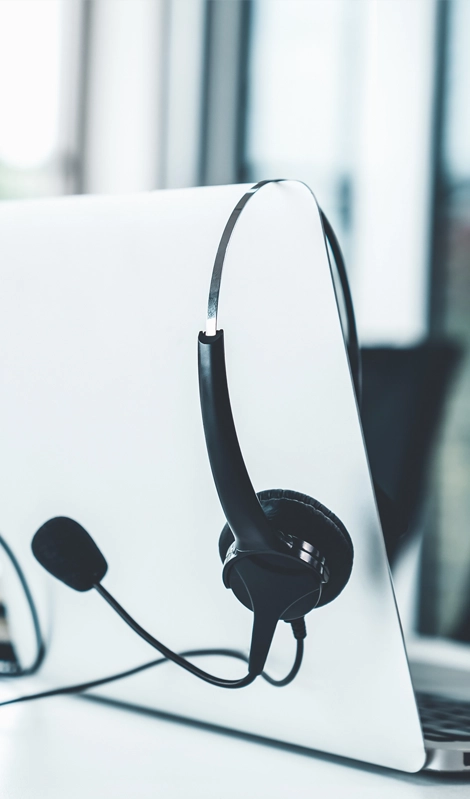 Un ordenador portátil con un auricular de agente telefónico que reposa sobre él
