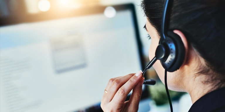 over-the-shoulder shot of a woman in a headset looking at a computer screen