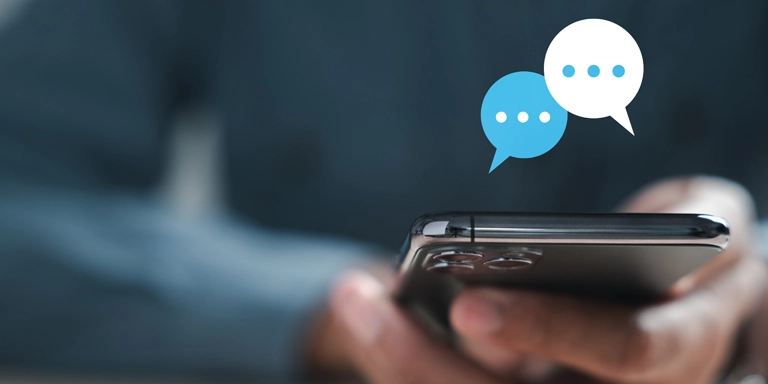 hand holding cell phone with digital word bubbles above it